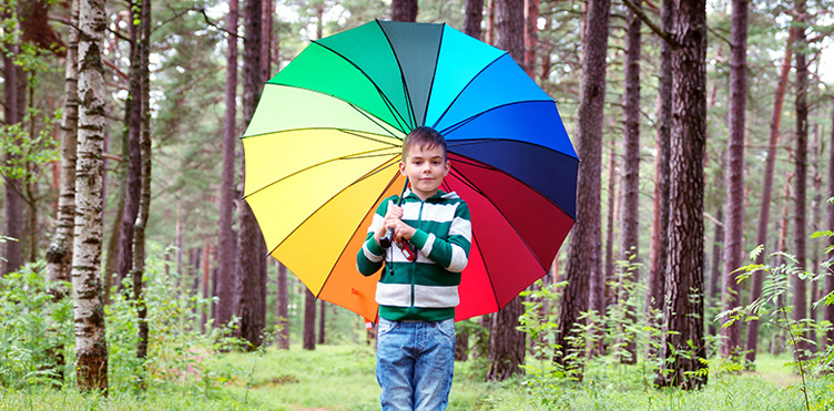 Young boy holding a rainbow umbrella