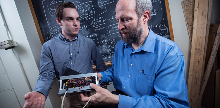 Electrical engineering student Atlin Anderson and Associate Professor Dr. Brent Petersen examine a CubeSat.