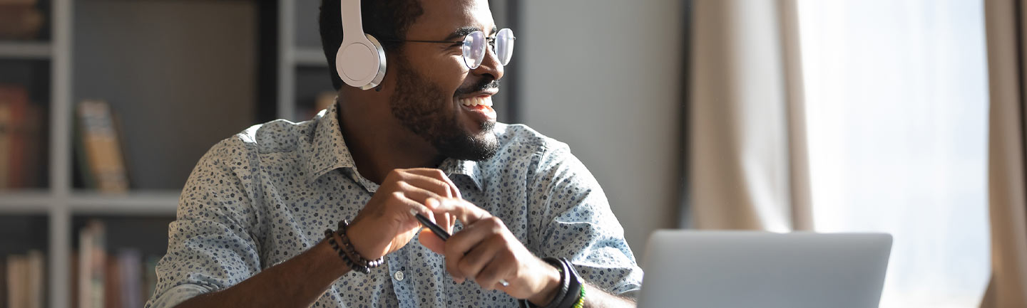 Man wearing headphones by a laptop