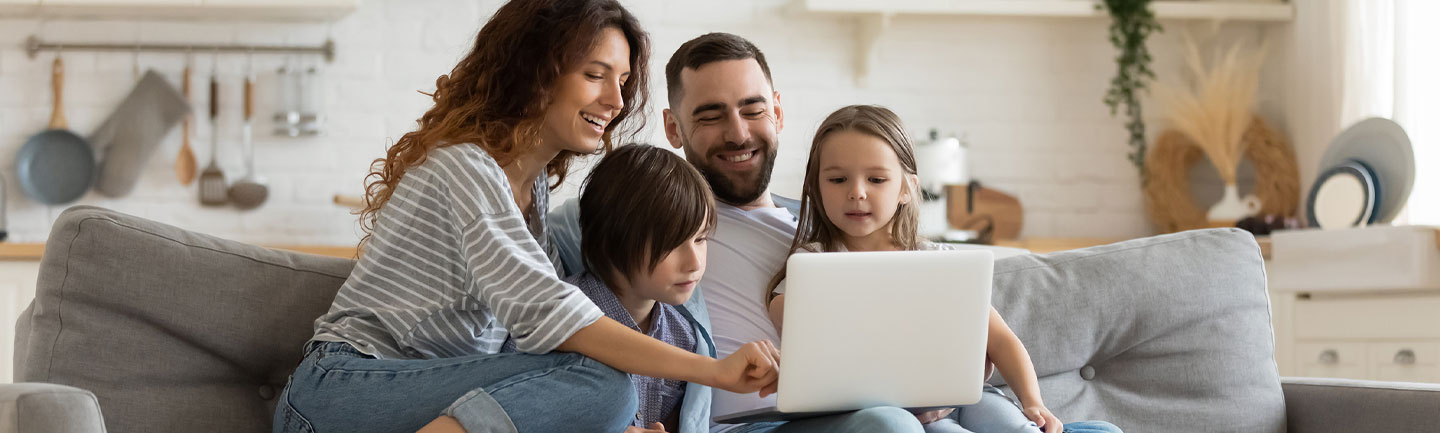 A family sitting on a couch looking at a laptop