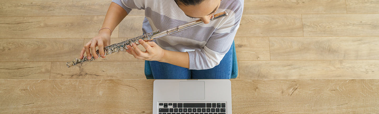 Woman on her laptop playing the flute
