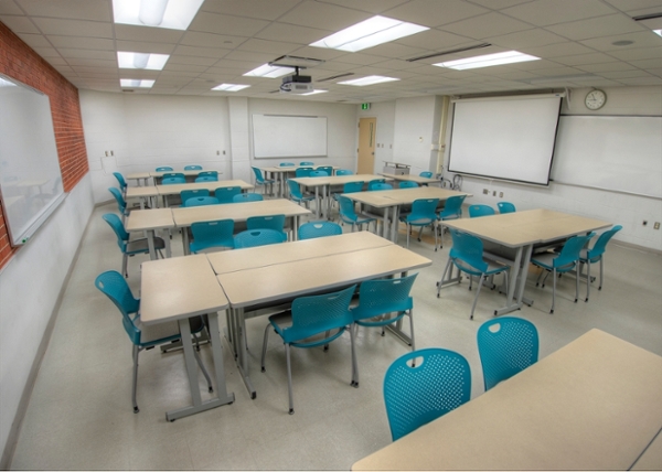 Groups of tables arranged in a classroom to allow for flexibility in setup along with whiteboards to facilitate learning