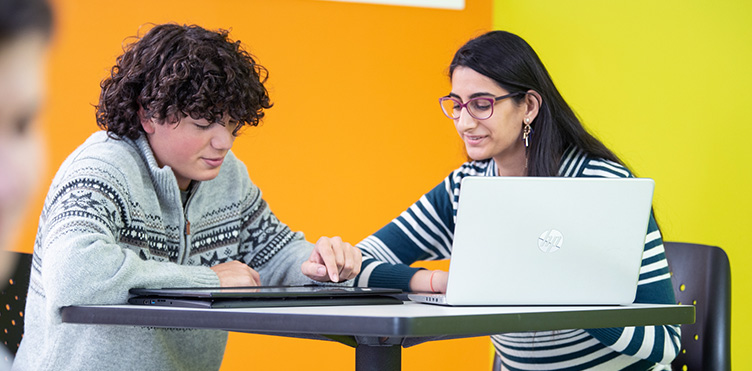 Two computer science students in a brightly-coloured room study together.