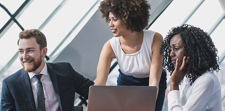 Three individuals in a classroom with a computer