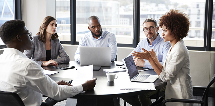 Team of professionals gathered around a table having a discussion in a meeting room.