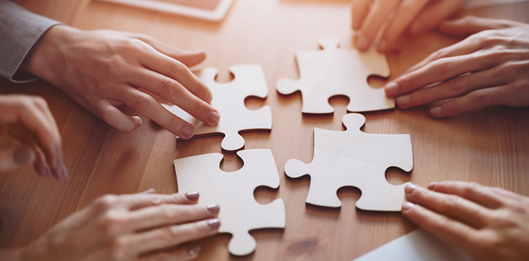 Four large puzzle pieces are in the centre being moved to fit together.