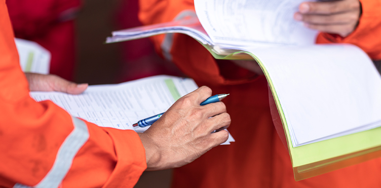 Workers in safety uniforms reviewing inspection documents as part of a safety investigation.