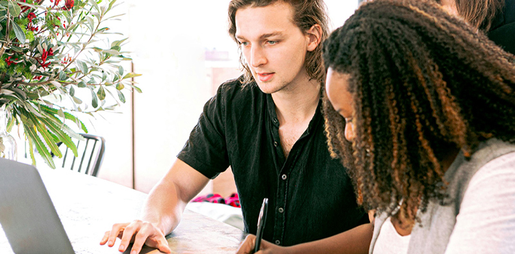 Students taking notes and looking at a laptop.