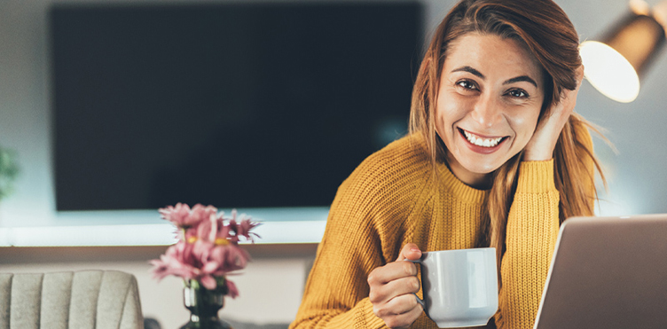 Photo of a happy professional with a laptop and holding a mug
